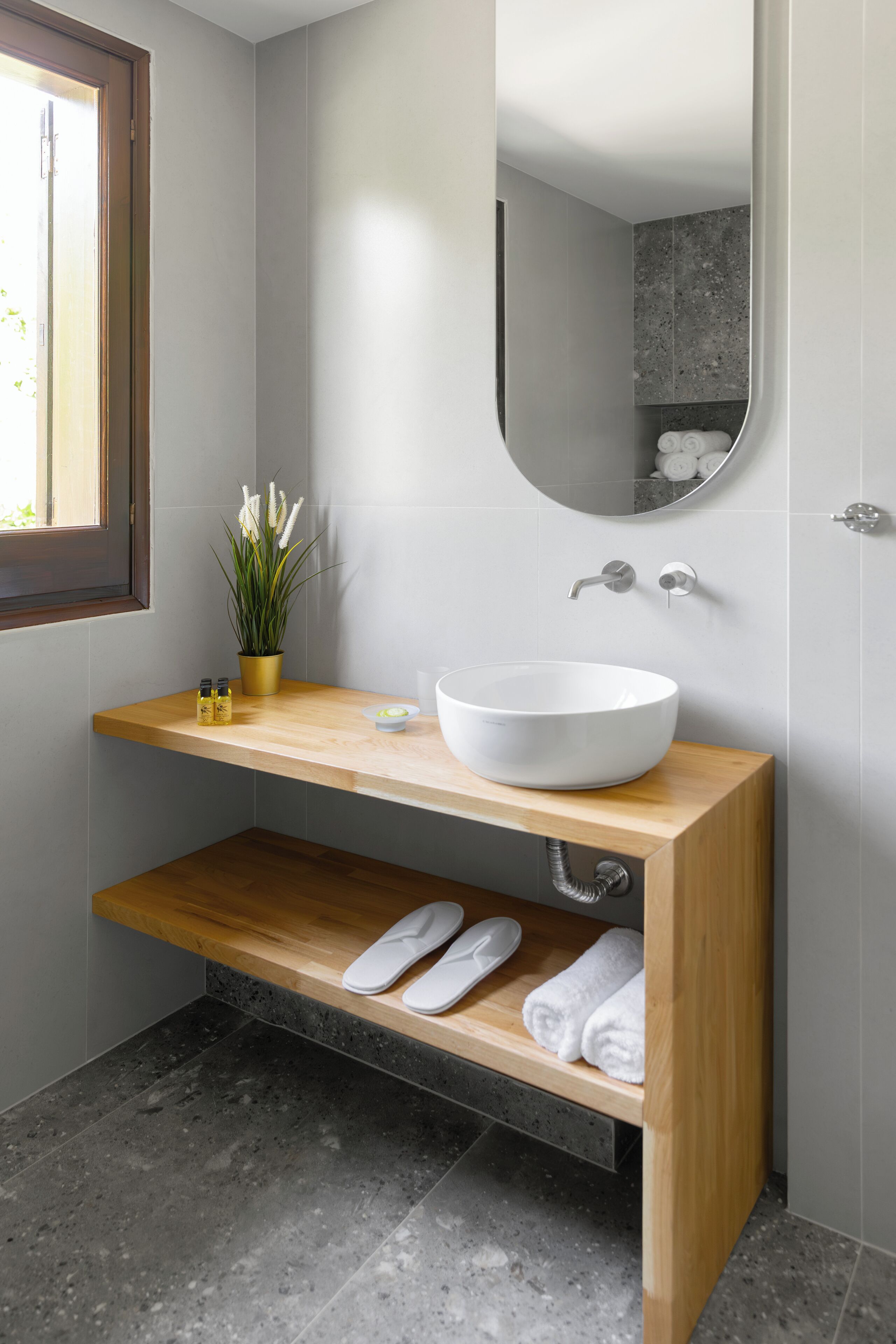 A modern bathroom with a wooden vanity, white sink, and a mirror above it.
