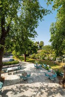 An outdoor patio with stone flooring, green chairs, and tables.