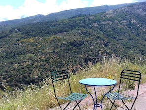 A table and two chairs on a terrace overlooking a mountainous landscape. - Ikarian Centre (Ikaria)