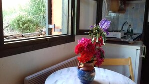 Una pequeña mesa redonda con un jarrón de flores en una maceta de cerámica azul.