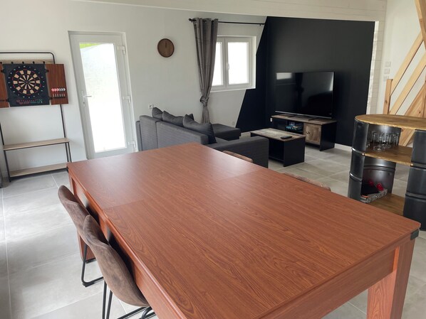 Una sala moderna con una mesa de comedor de madera, un sofá gris y un mueble para televisión.