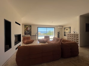 Un salon moderne avec un grand canapé d’angle, un téléviseur à écran plat et des œuvres d’art accrochées aux murs.