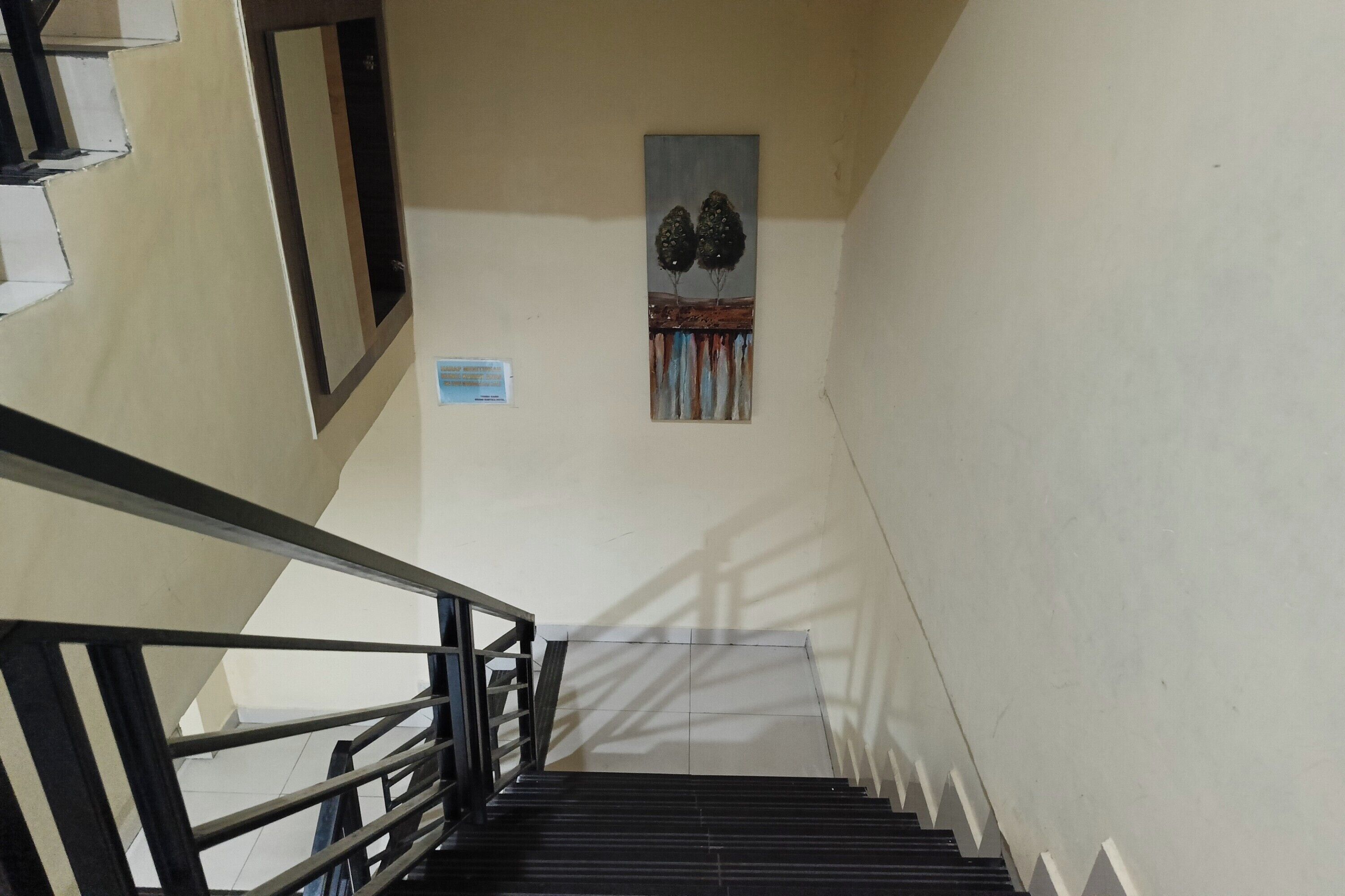 Una escalera con barandilla, una obra de arte en la pared y un cartel.