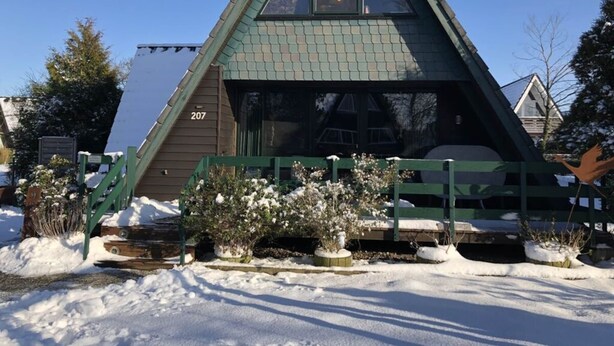 Un bâtiment de forme triangulaire, portant le numéro « 207 » sur l’un de ses côtés, et entouré d’un sol et de plantes recouverts de neige.