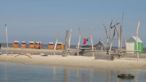 Une plage avec des structures en bois et un petit abri vert.
