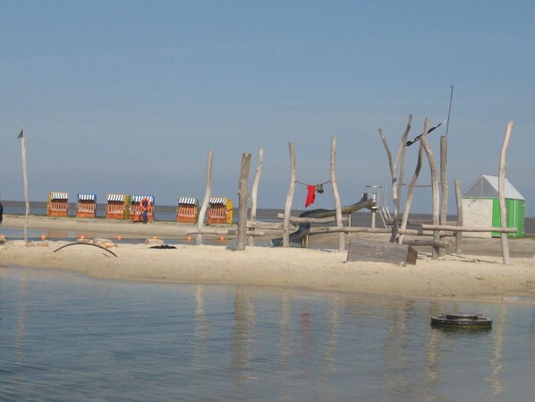 Una playa con estructuras de madera y un pequeño cobertizo verde.
