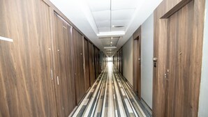 Un pasillo largo y estrecho con puertas de madera a ambos lados y un suelo a rayas.