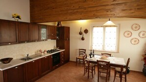 A kitchen with wooden cabinets, a tiled backsplash, a dining table with chairs, and a window with decorative plates. - Villa With Private Pool in Piancastagnaio (Piancastagnaio)