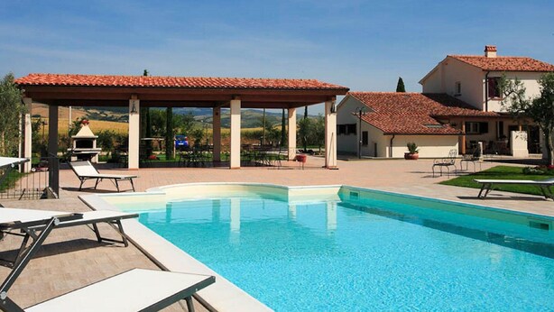 A swimming pool with lounge chairs, a covered patio, and a building with a red-tiled roof. - Villa With Private Pool in Piancastagnaio (Piancastagnaio)