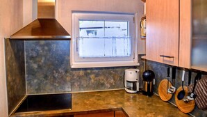 A kitchen with a window, a coffee maker, and wooden utensils hanging on the wall. - Peaceful Garden Apartment (Fuessen)