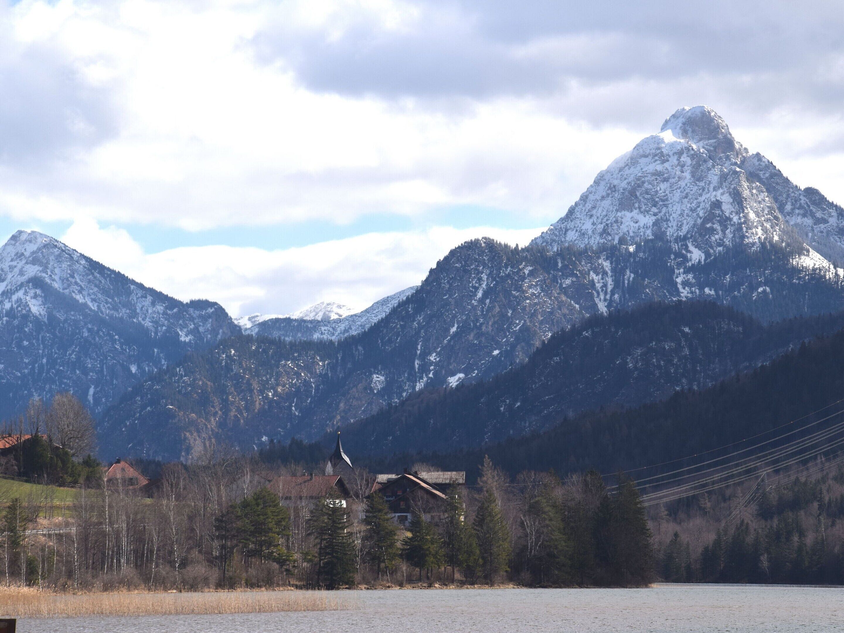 A mountain landscape with a lake, a church, and a building with a sloped roof.