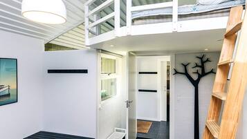 A loft bedroom with a bunk bed, a desk, and a ladder.