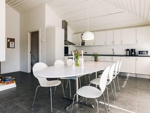 Une cuisine moderne avec des meubles blancs, une table de salle à manger ronde et des chaises blanches.