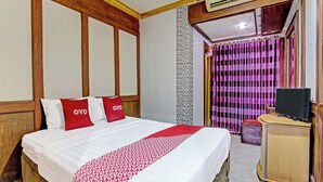 Une chambre d’hôtel avec un lit, une télévision et une armoire en bois.