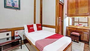 Une chambre d’hôtel avec un lit, des meubles en bois, un bureau et une armoire.