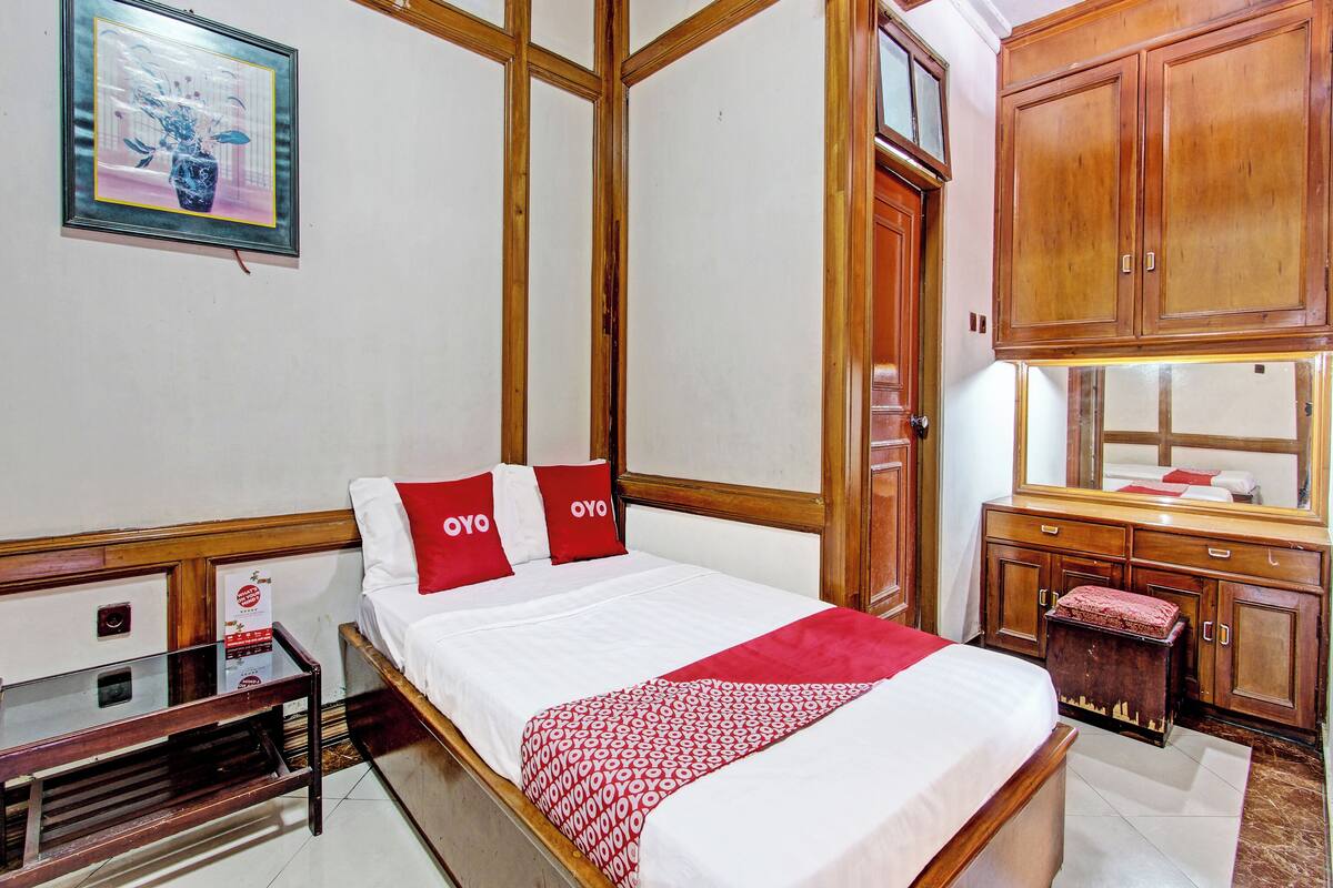 Une chambre d’hôtel avec un lit, des meubles en bois, un bureau et une armoire.