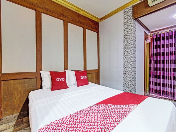 A hotel room with a large bed, wooden headboard, and a red and white patterned bedspread. - Hotel O Bugisan (Yogyakarta)