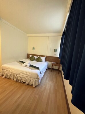 A hotel room with two beds, wooden flooring, and a window with dark curtains. - Asia Inn Bangkok 2022 (Bangkok)