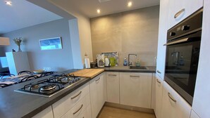 A modern kitchen with a gas stove, a sink, and a built-in oven. - Apartment in Nieuwpoort With Ocean Views (Nieuwpoort)