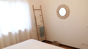 Ein Schlafzimmer mit einem Bett, einer Leiter, einem runden Spiegel und einem gewebten Korb.