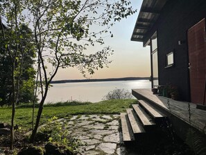 Uma trilha de pedra leva a um deck de madeira com vista para um lago.