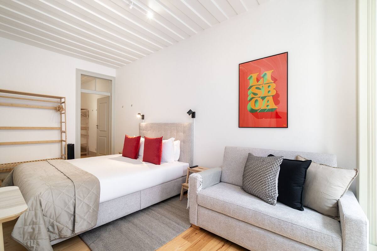 Une chambre d’hôtel moderne équipée d’un lit, d’un canapé, d’une table de chevet et d’une œuvre d’art accrochée au mur.