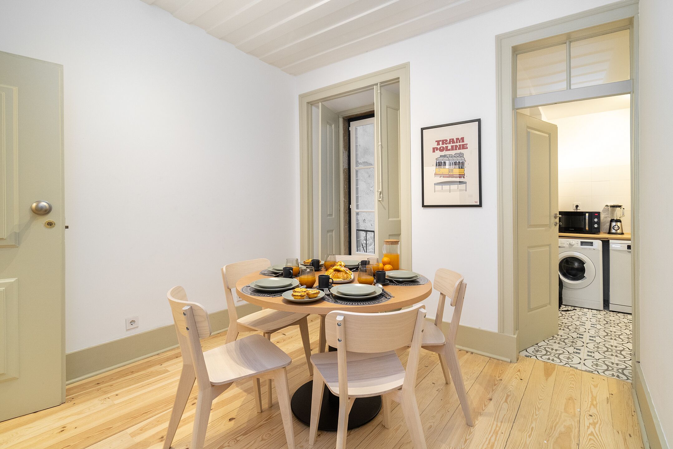 Un comedor con una mesa redonda, cuatro sillas y una disposición para el desayuno.