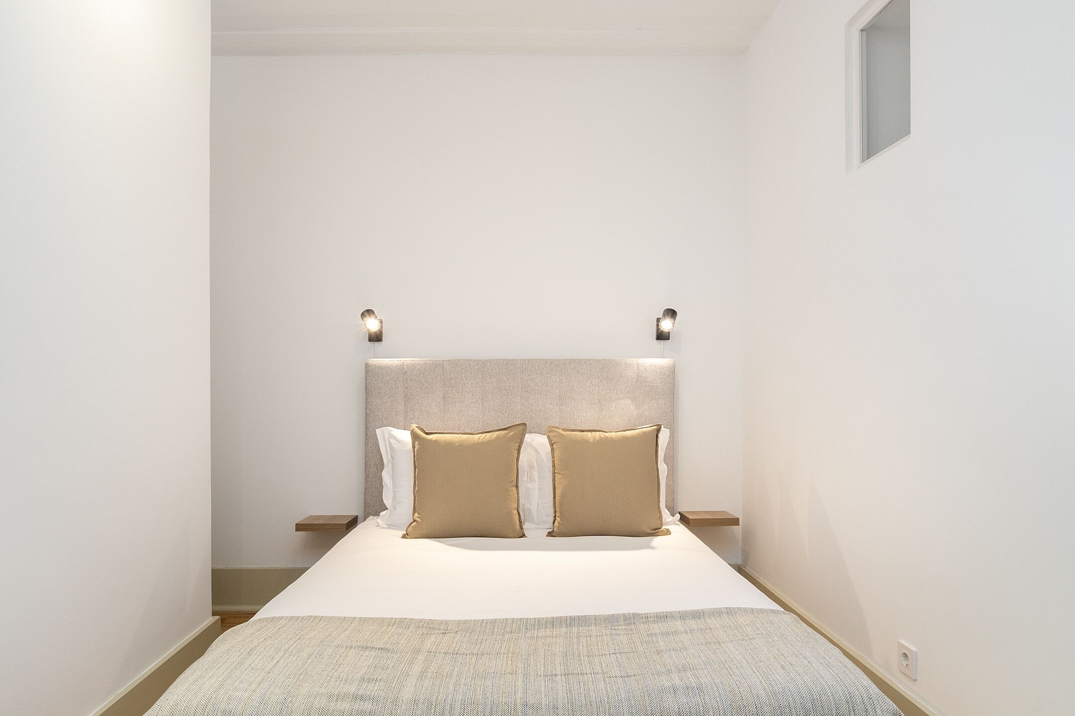Een keurig opgemaakt slaapkamer met een bed, twee nachtkastjes en een hoofdbord met verlichting.