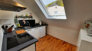 Une cuisine moderne dotée d’une verrière, d’un plancher en bois et offrant une vue sur la maison voisine.