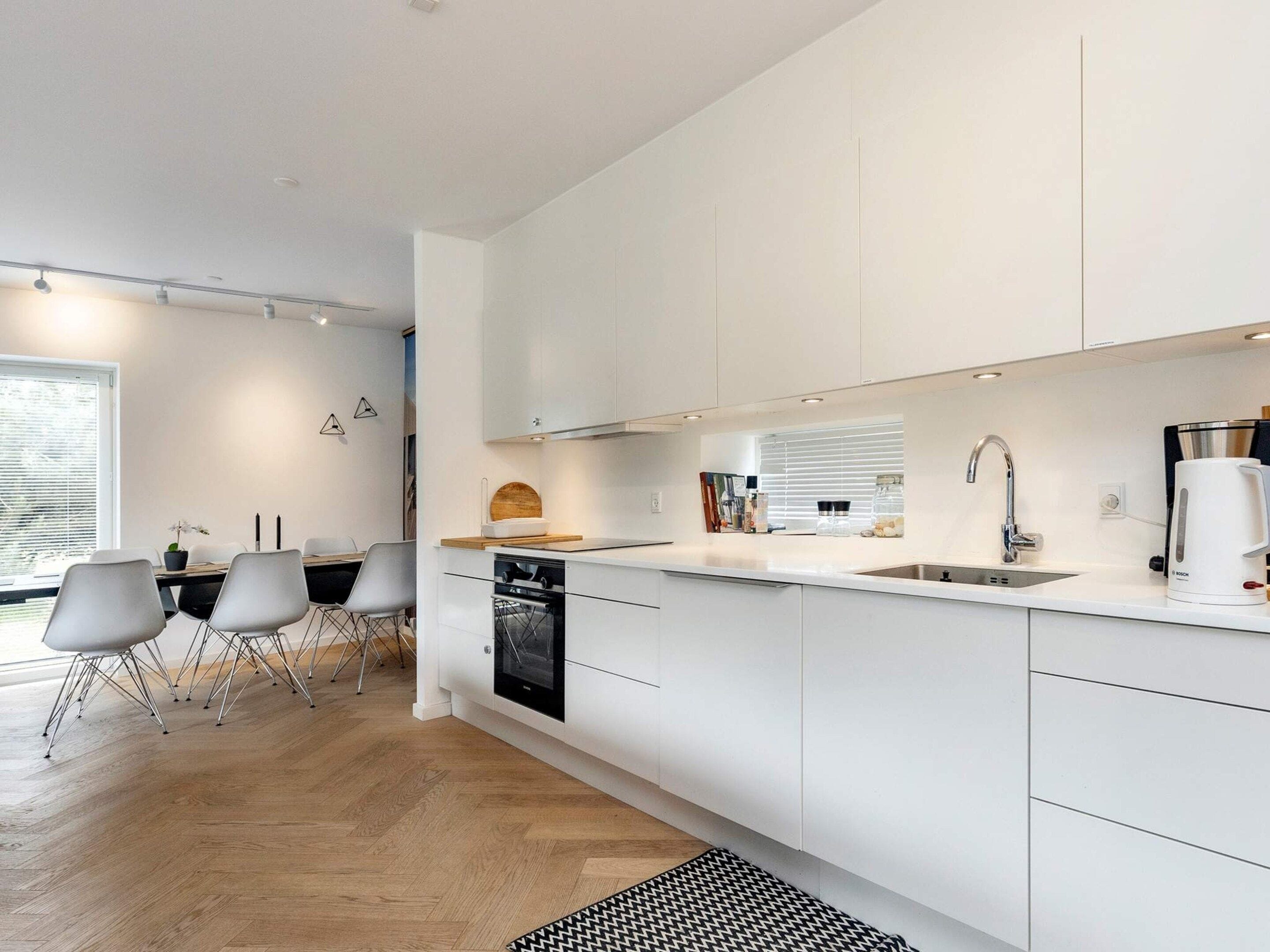 A modern kitchen with white cabinetry, a built-in oven, and a Bosch coffee maker.