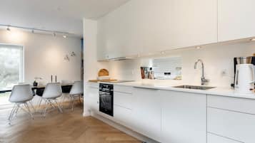A modern kitchen with white cabinetry, a built-in oven, and a Bosch coffee maker.
