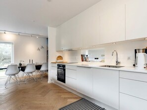 A modern kitchen with white cabinetry, a built-in oven, and a Bosch coffee maker. - 4 Star Holiday Home in Vaeggerlose (Vaeggerlose)