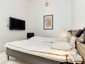 A bedroom with a bed, a wall-mounted TV, a framed artwork, and a bedside lamp. - 4 Star Holiday Home in Vaeggerlose (Vaeggerlose)