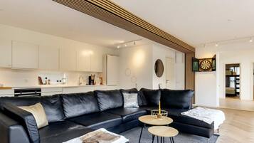 A modern living room with a black leather sectional sofa, two round coffee tables, and a white rug.