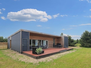 A modern house with a covered patio, a small garden, and a wooden deck.