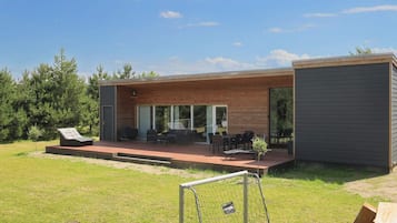 A modern house with a patio, outdoor seating, and a small garden.