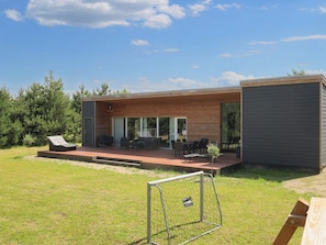 A modern house with a patio, outdoor seating, and a small garden. - 4 Star Holiday Home in Vaeggerlose (Vaeggerlose)