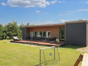 A modern house with a patio, outdoor seating, and a small garden. - 4 Star Holiday Home in Vaeggerlose (Vaeggerlose)