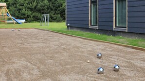 A courtyard with a children's play area, including a slide and a goalpost, and a building with large windows. - 4 Star Holiday Home in Vaeggerlose (Vaeggerlose)