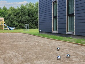 A courtyard with a children's play area, including a slide and a goalpost, and a building with large windows. - 4 Star Holiday Home in Vaeggerlose (Vaeggerlose)