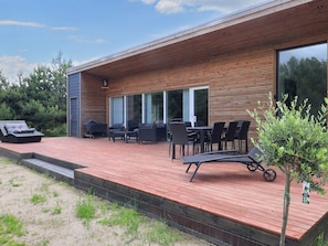 A modern outdoor deck with a wooden floor, outdoor furniture, and a grill. - 4 Star Holiday Home in Vaeggerlose (Vaeggerlose)