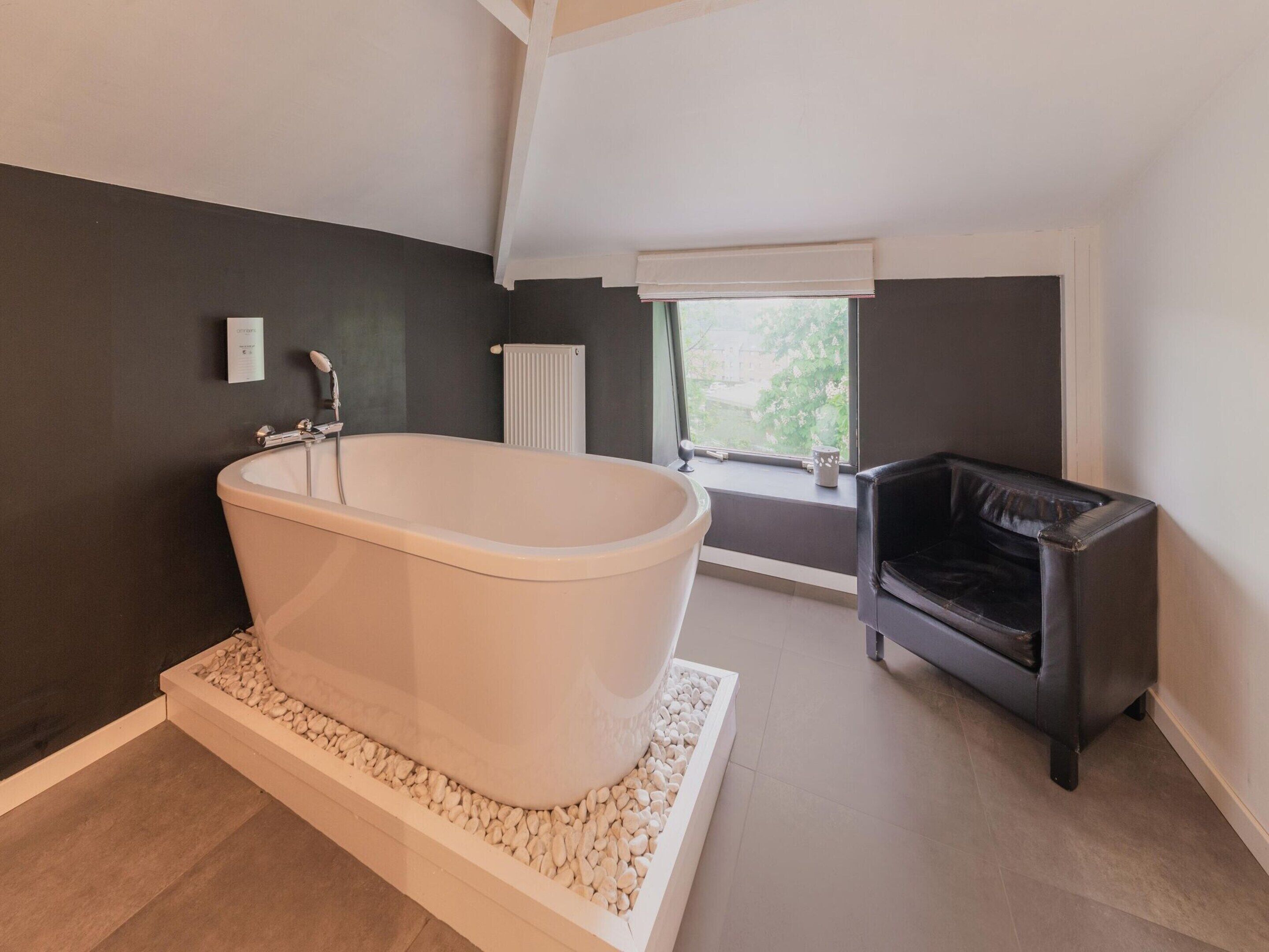 A modern bathroom with a freestanding bathtub, a radiator, and a window with a view.