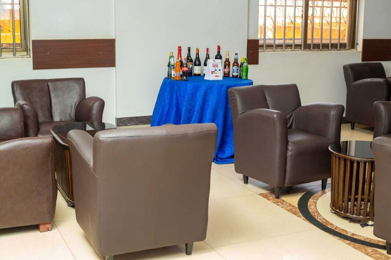 Une pièce avec des canapés en cuir marron, une table bleue sur laquelle sont posées des bouteilles d’alcool, et une petite poubelle.