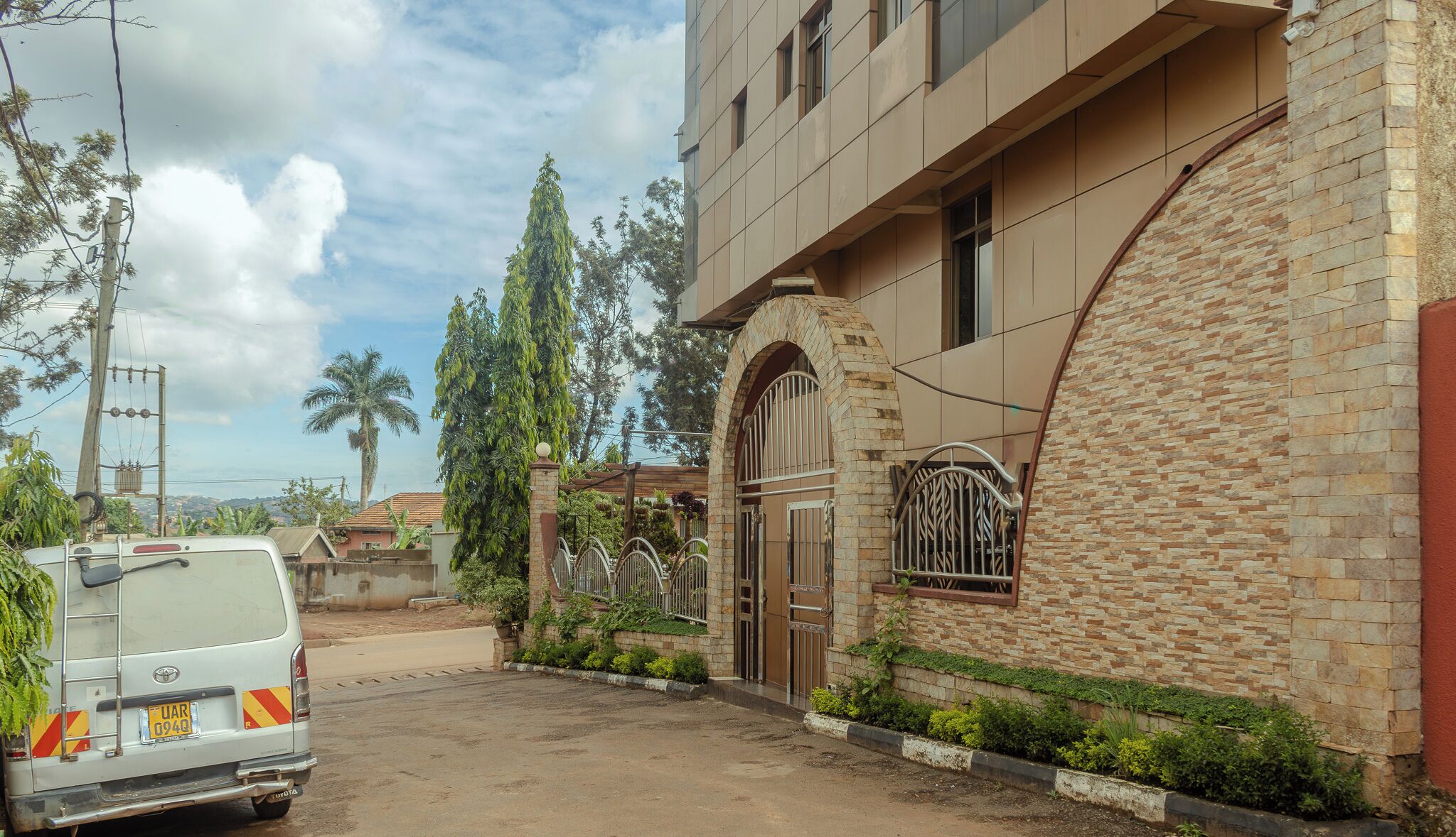A residential building with a stone facade, a gated entrance, and a parked van.