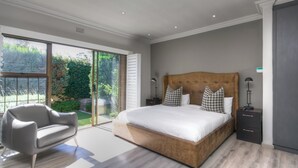 Ein modernes Schlafzimmer mit einem großen Bett, einer Couch und einer Schiebeglastür, die auf einen Balkon führt.