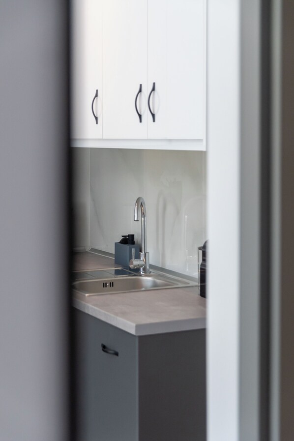 Une cuisine moderne avec des meubles blancs, un évier en acier inoxydable et un distributeur de savon bleu.