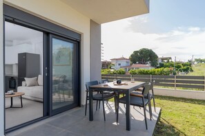 A modern outdoor dining area with a table and chairs, a sofa, and a sliding glass door leading to a kitchen. - SithoniaRS Ground Floor Gem in Nikiti (Nikiti)