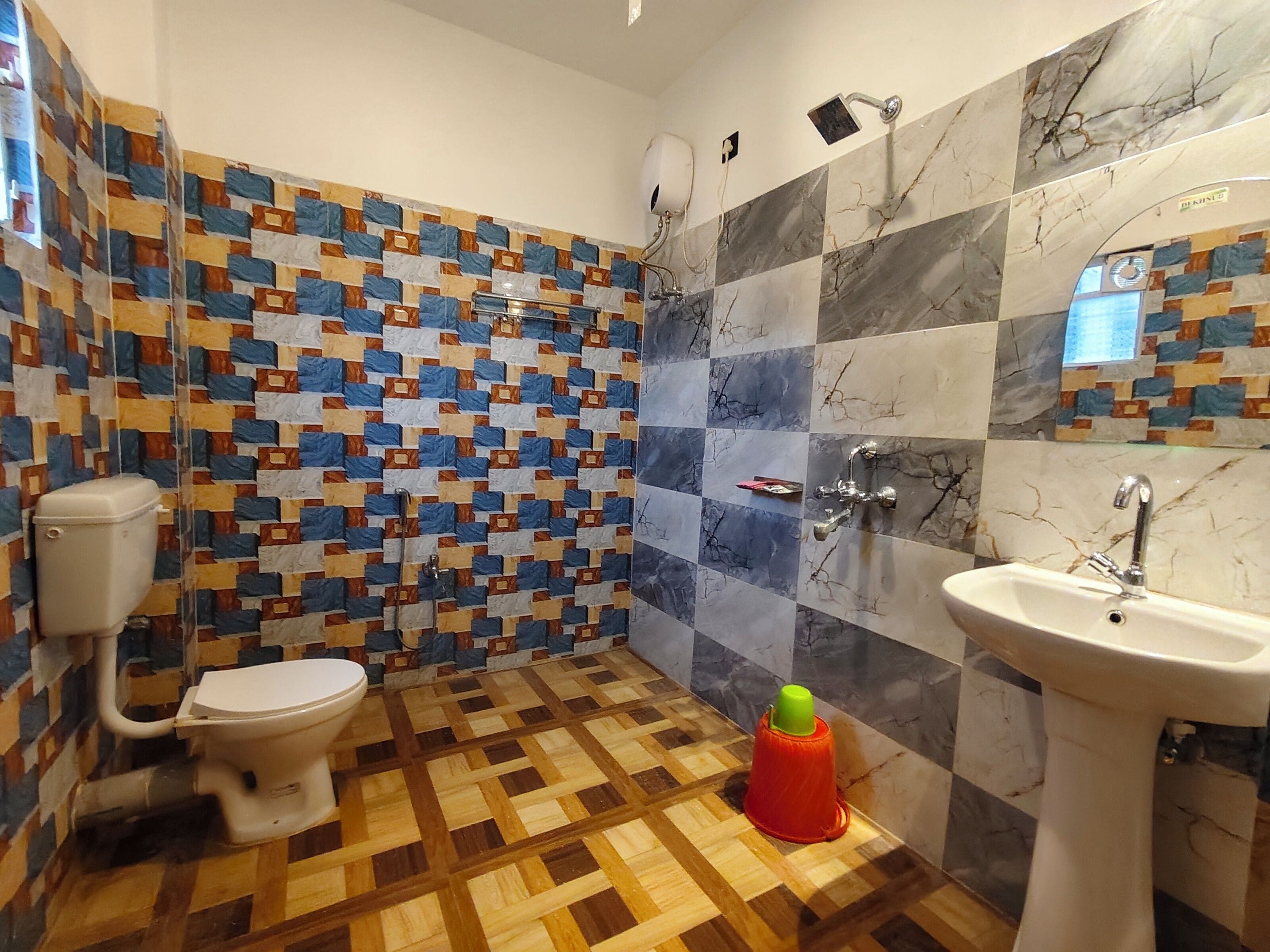 Baño con inodoro, ducha y lavamanos. Las paredes tienen un diseño de azulejos estampados.