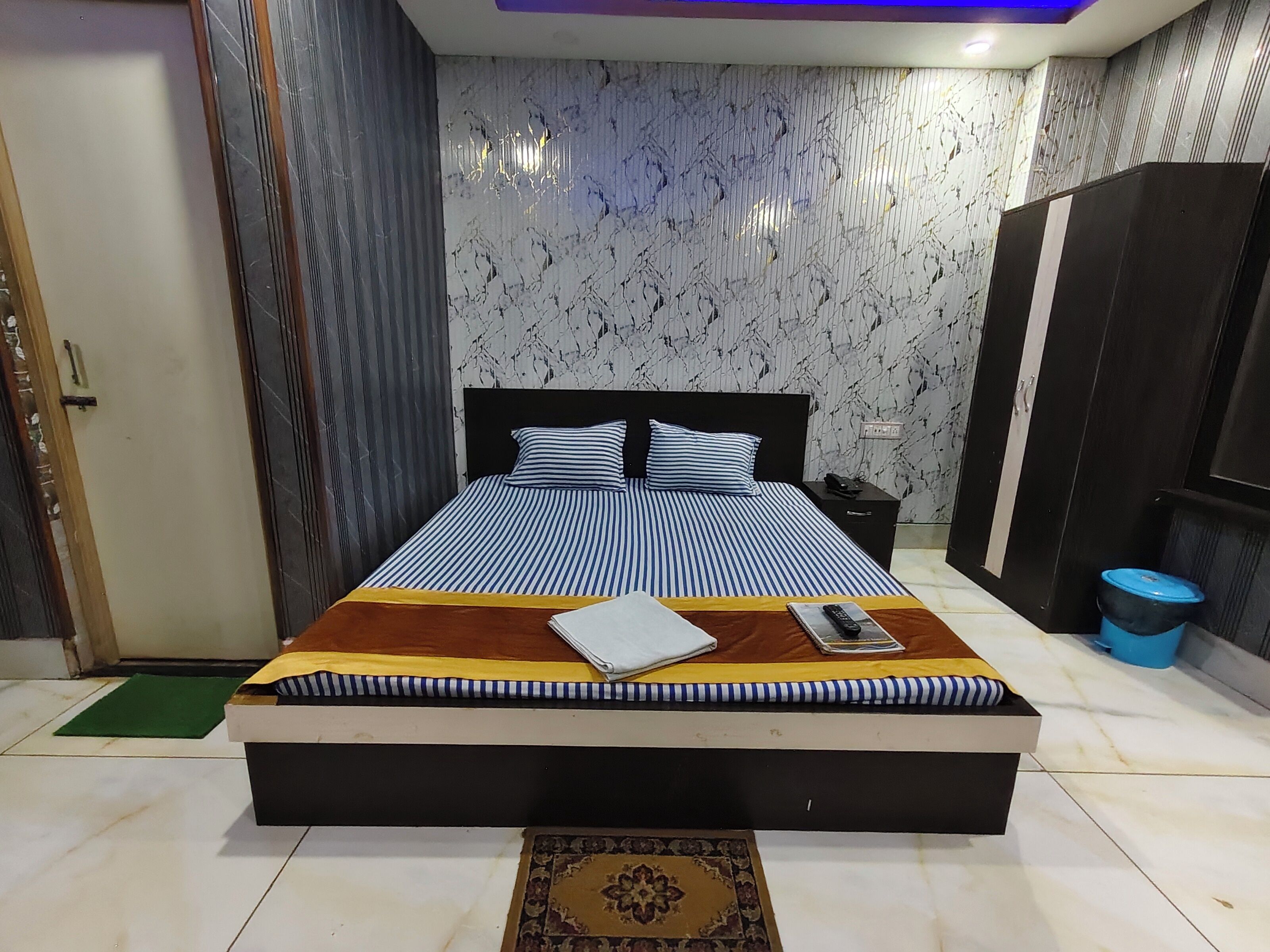 A modern bedroom with a large bed, a bedside table, a nightstand, and a wardrobe.