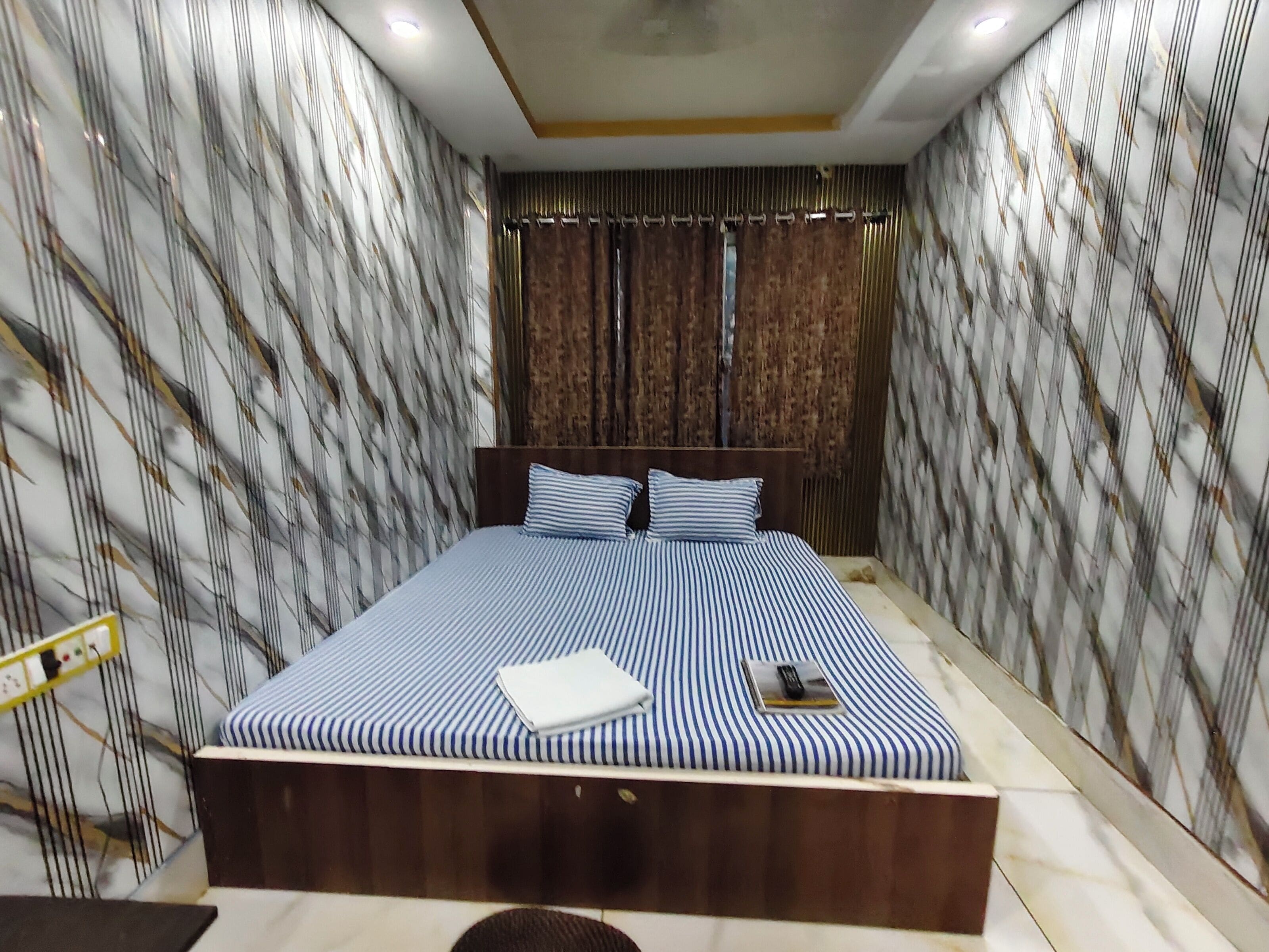 A bedroom with a large bed, wooden headboard, and patterned wallpaper.